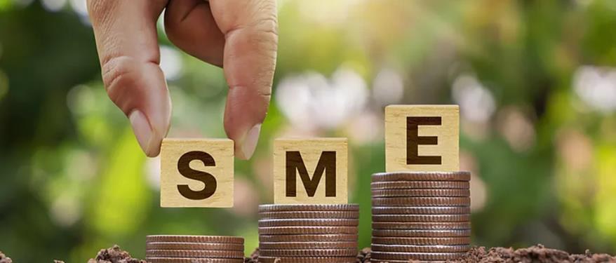 مكعبات خشبية مكتوب عليها SME فوق عملات معدنية، رمزًا لتمويل الشركات الصغيرة والمتوسطة